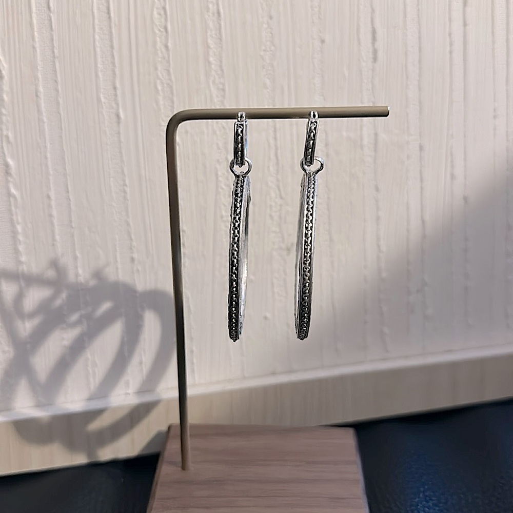 Stamped 2.5 inch KC earrings in silver tone with silver leather on both sides.